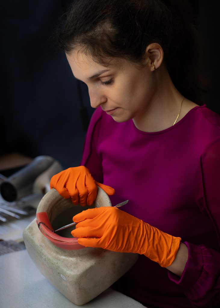 Sophie Genin, restauratrice de céramique et verre en cours de traitement de restauration sur une oeuvre en grès contemporain dans son atelier à Bruxelles présentation à propos contact formée en histoire de l'art